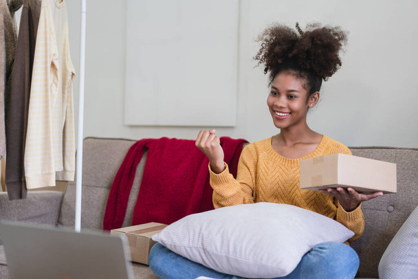 Africaine américaine marchand de mode femme lever le bras avec bonheur tandis que vérifier commande en ligne sur ordinateur portable. - Photo, image