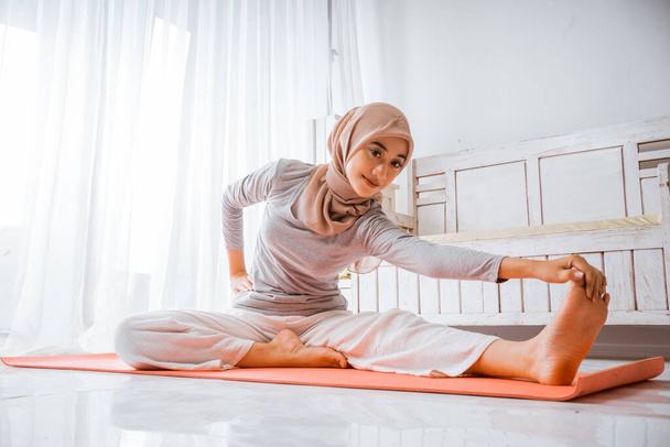 Asyalı Müslüman kadın eğitmen yoga pilatesi giyip turuncu yatakta poz veriyor. - Fotoğraf, Görsel