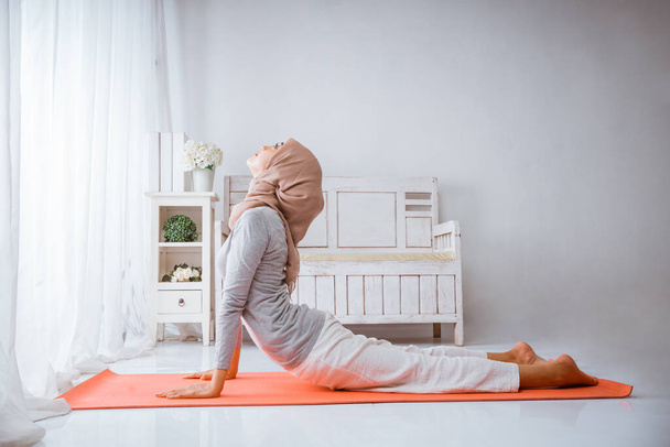 asian muslim woman instructor training bhujangsana cobra yoga pose wearing hijab on pilates matress - Fotoğraf, Görsel