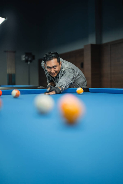 portrait of the male billiard player smiling while poking the ball during the billiard game - Foto, Bild