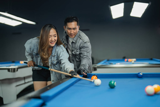 female pool player guided by the male pool player while poking the white ball - Photo, Image
