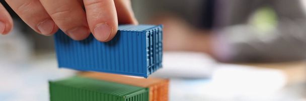 Stack of cargo containers on financial report papers and blurred business man. Logistics, shipping, freight transportation and deliver cargo containers worldwide. Imports, export of goods - Photo, Image