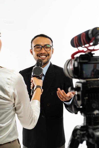 an adult men in blue shirt and black suit with eye glasses smiling to the camera when interviewed by a journalist - Fotoğraf, Görsel