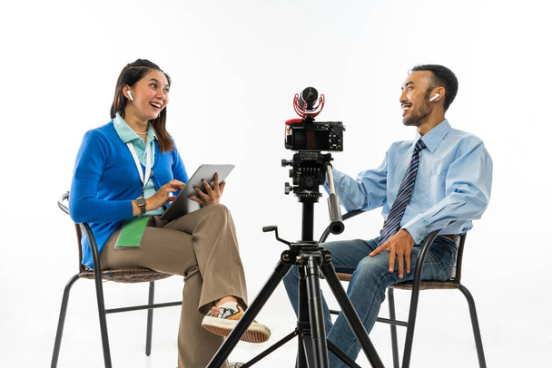 a female journalist in blue cardigan and an adult man in blue shirt sitting on chair while doing an interview - Φωτογραφία, εικόνα