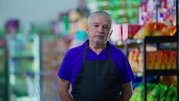 Serious concerned senior employee of supermarket standing inside business. One older caucasian manager wearing apron with preoccupied expression - Footage, Video