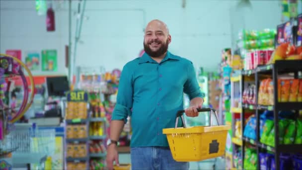 Happy Brasilian mies seisoo ruokakaupassa pitäen kori kädessä hymyillen kameralle, kuluttajien tottumukset Etelä-Amerikan supermarket shopper - Materiaali, video
