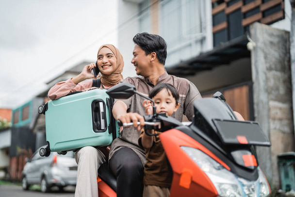 asian muslim family riding motorbike scooter together traveling with kid. eid mubarak travel concept - Photo, Image