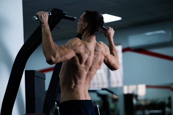Back view of shirtless man with pull-ups in gym - Foto, Bild