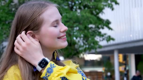 straighten hair with hands long dangling earrings in blue and yellow embroidery blue flowers. girl is wearing an embroidered shirt, national Ukrainian Slavicclothes, a yellow shirt.  - Footage, Video