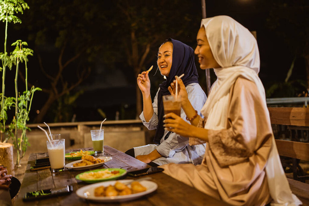 Asian young woman in hijab meal while breaking fast at outdoor cafe - Fotó, kép