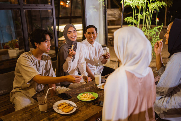 eine Gruppe muslimischer Frauen und Männer isst Snacks und trinkt, während sie gemeinsam in einem Restaurant im Freien fasten - Foto, Bild