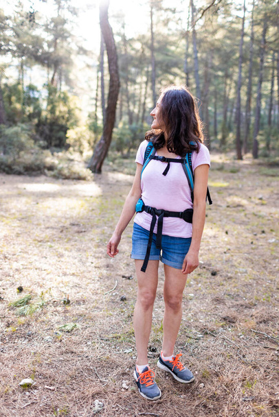 Egy nő hátizsákkal. Életmód kaland koncepció erdő és hegyek hátterében szabadtéri tevékenységek a vadonban. fiatal lány mosolyog a kamerába. - Fotó, kép