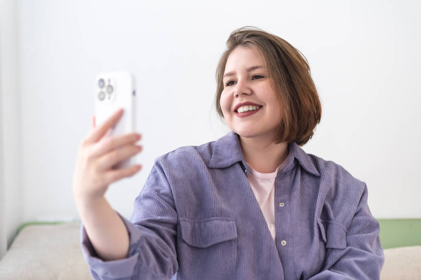 Plus velikost usmívající se mladá žena brát selfie s mobilním telefonem. - Fotografie, Obrázek