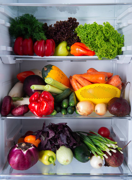 Open refrigerator full of fresh ripe seasonal vegetables. The concept of diet, healthy eating and vegetarianism - Photo, image