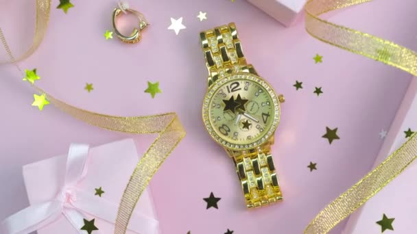 Вращающийся фон различных модных женских аксессуаров, часов и подарочных коробок с золотыми лентами на розовом фоне крупным планом - Кадры, видео