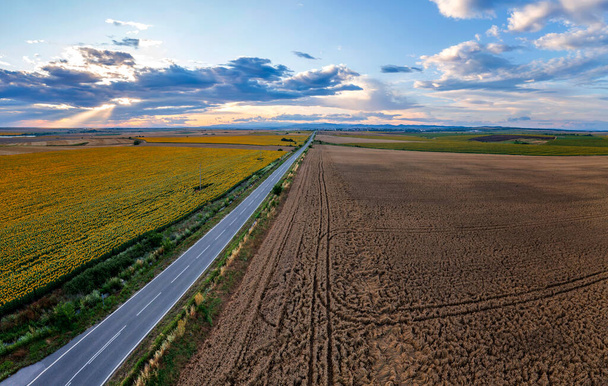 vista aérea de un paisaje rural con una carretera asfaltada, contra el atardecer - Foto, imagen