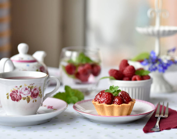 Mini tarts with raspberries served with tea on the table - 写真・画像