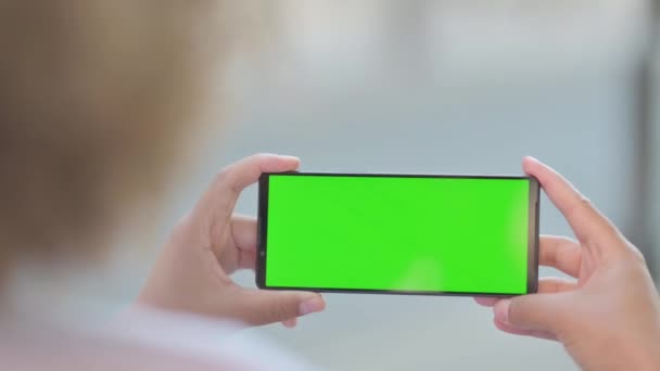 Африканська жінка тримає телефон горизонтально з зеленим екраном, на відкритому повітрі - Кадри, відео