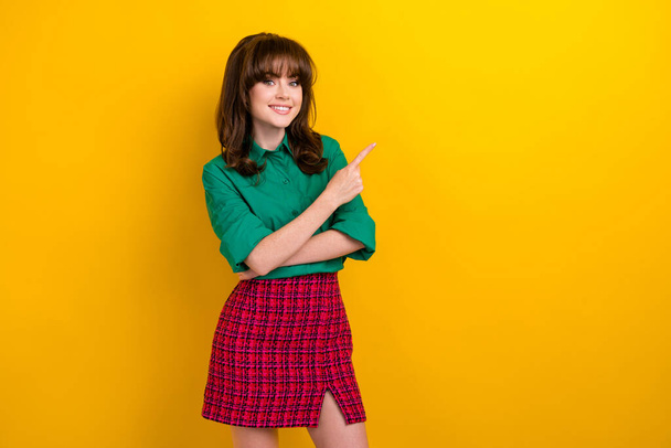 Photo of sweet shiny lady wear green shirt pointing finger empty space isolated yellow color background. - 写真・画像