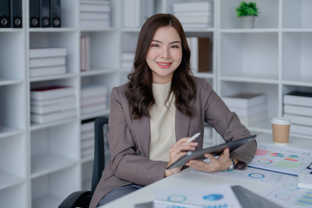 businesswoman in a black suit inside the office using tablet computer, audit paperwork for customers to contact, business people concept - Photo, image