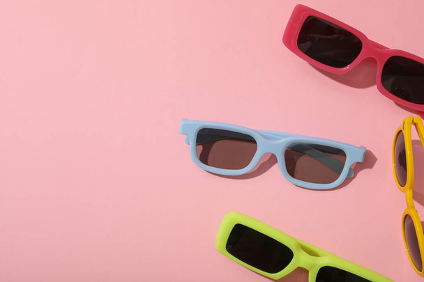 Gafas de sol de colores sobre fondo rosa, espacio para texto - Foto, imagen
