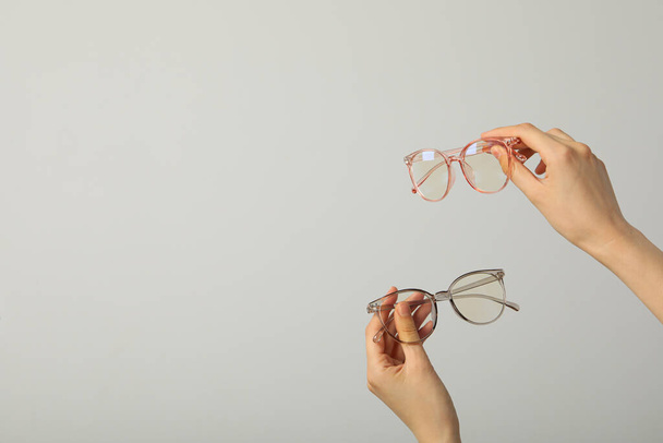 Glasses in female hands on light gray background, space for text - 写真・画像