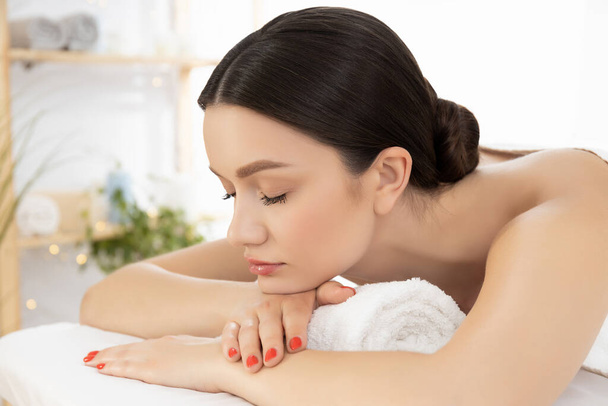 Giovane donna rilassata sul massaggio nel salone SPA, sfondo chiaro - Foto, immagini