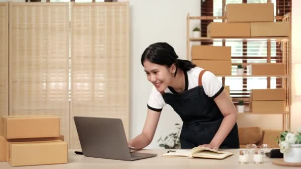 Başlangıçta küçük işletme KOBİ 'si, dizüstü bilgisayar kullanan girişimci kadın paket ürün kutusu hazırlamak için çevrimiçi alışveriş siparişini alır ve kontrol eder. - Video, Çekim