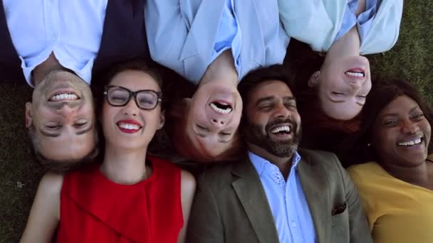 biznesmeni leżący twarze razem, szczęśliwi wielorasowi ludzie patrzący w górę - Materiał filmowy, wideo