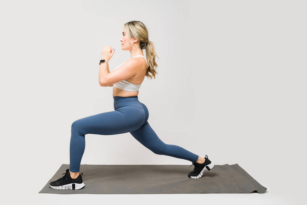 Attrayant athlète femme en leggings faire squats bulgares tout en travaillant sur son corps en forme et butin  - Photo, image