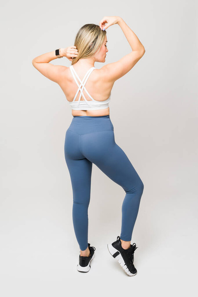 Athletic woman with sporty leggings showing her strong back muscles and fitness booty while posing after exercising - Fotoğraf, Görsel