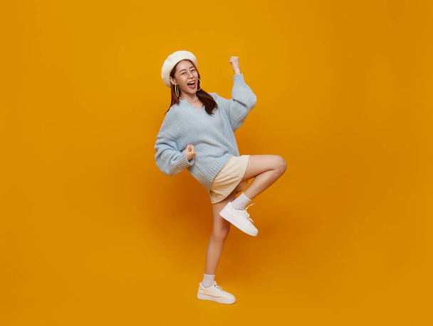 Excited young asian teen female with raised hands celebrating success Portrait cheerful positive asian woman with raised hands and fists open mouth Girl get happy isolated on yellow background. - Foto, imagen