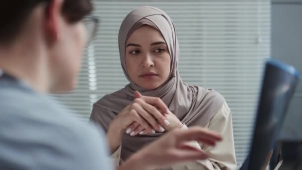 Jonge moslim vrouwelijke patiënt in hijab luisteren naar clinicus uit te leggen details van x-ray beeld met de resultaten van medisch onderzoek van longen of thorax tijdens overleg in klinieken - Video