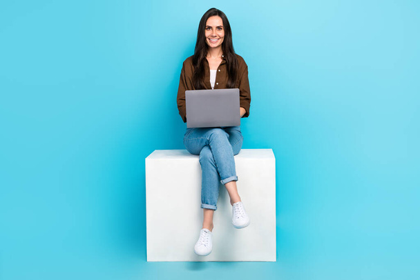 Full length body photo of girl sitting podium internet job virtual copywriting artificial intelligence isolated on blue color background. - Фото, изображение
