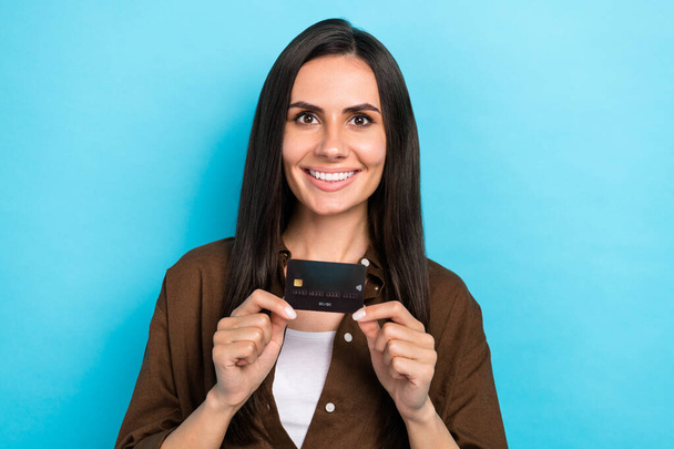Photo of sweet cheerful lady wear brown shirt smiling holding showing credit card isolated blue color background. - Φωτογραφία, εικόνα