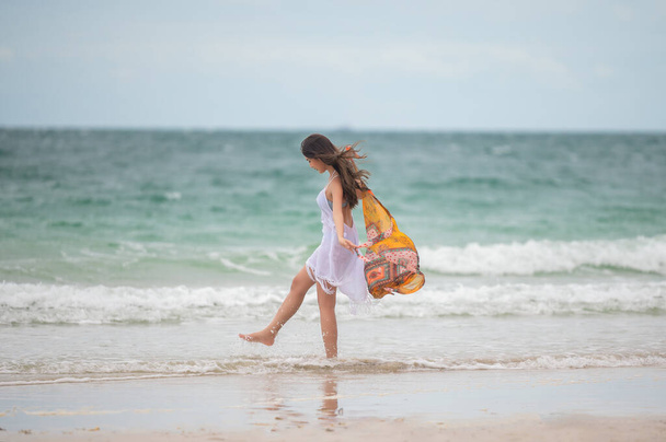 Woman traveler in dress laying walks relax on the sea beach, enjoy moment on the sea summer - Fotografie, Obrázek