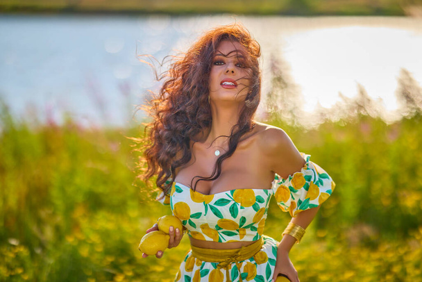 portrait of a beautiful woman with lemons on a meadow near a lake. - Fotografie, Obrázek