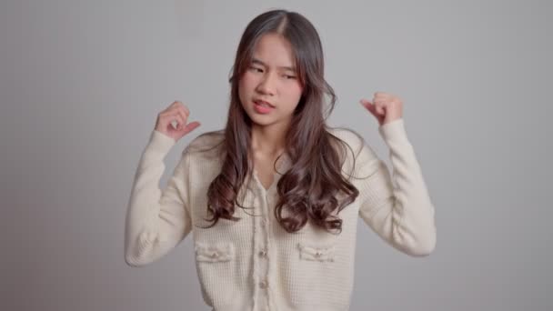 Ritratto di ragazza hipster arrabbiata e triste asiatica su sfondo bianco, L'emozione di un hipster quando capriccio e pazzo, espressione di emozione scontrosa. Concetto di controllo emotivo adolescente - Filmati, video