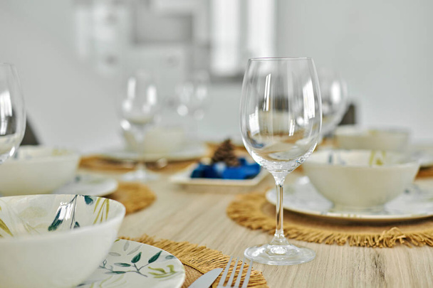 El primer plano de copas de vino vacías y vajilla está listo para el almuerzo servido en la mesa de comedor, sin personas. Celebración de eventos de vida, cenar en casa - Foto, Imagen