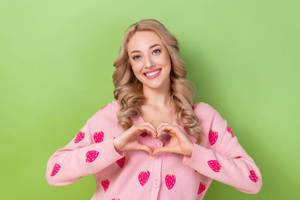 Portrait of positive pleasant pretty adorable woman wear stylish sweatshirt fingers show heart symbol isolated on green color background. - Photo, image