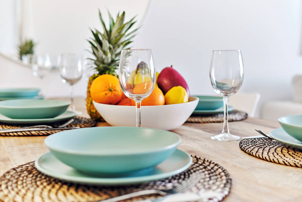 Close up shot on a dining table tropical fruits in bowl served with empty glass and plates for family dinner at home - Foto, Imagen