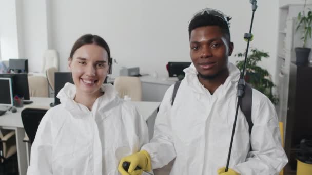 Portret odnoszącego sukcesy, zróżnicowanego etnicznie młodego mężczyzny i kobiety pracujących w firmie sprzątającej w apartamencie ochronnym, patrzących przed kamerą - Materiał filmowy, wideo