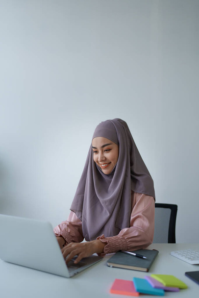 Muslim woman manager, lawyer or company employee holding accounting bookkeeping documents checking financial data or marketing report working in office with laptop. Paperwork management. - Photo, Image