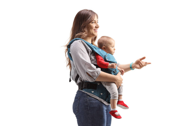 Profile shot of a mother standing with a baby in a carrier isolated on white background - Foto, Bild