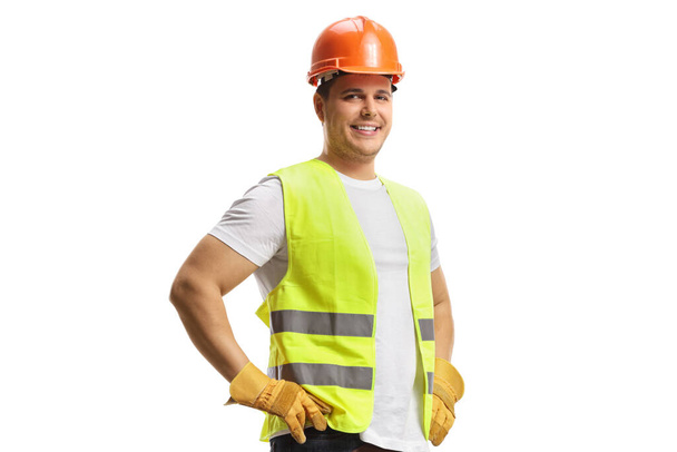 Stavební dělník s helmou a bezpečnostní vestou s úsměvem na kameru izolované na bílém pozadí - Fotografie, Obrázek