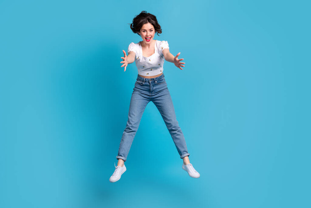 Full length photo of active overjoyed pretty person jumping falling raise arms isolated on blue color background. - Foto, afbeelding