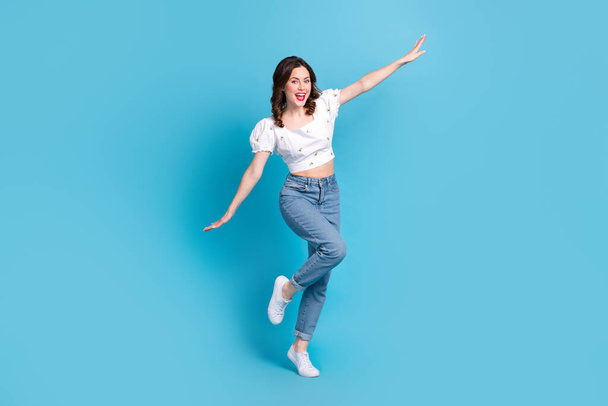 Full length photo of adorable carefree girl dressed white top flying arms sides isolated blue color background. - Фото, зображення