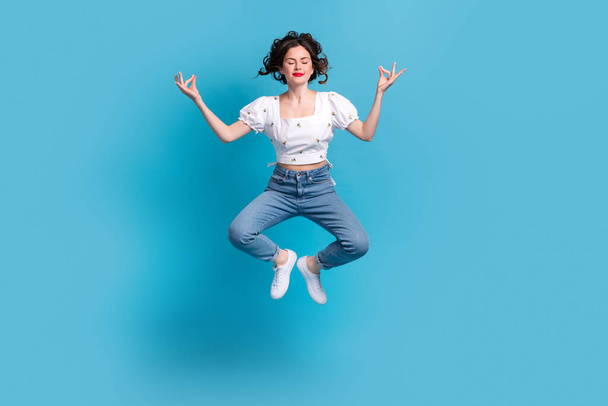 Full size portrait of carefree lovely girl jumping flying closed eyes meditate isolated on blue color background. - Zdjęcie, obraz