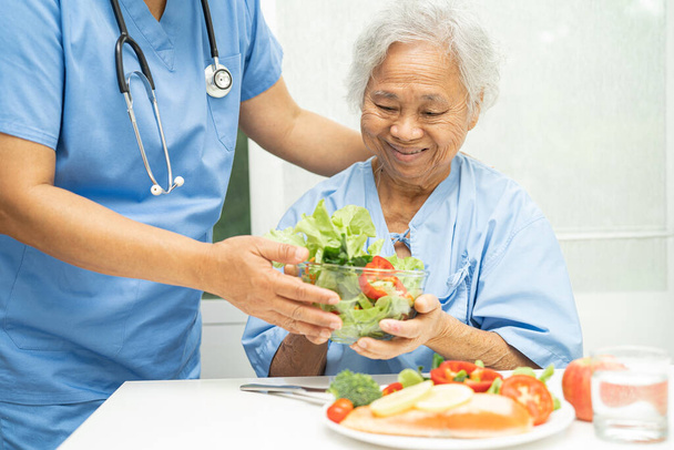 Asian elderly woman patient eating salmon steak breakfast with vegetable healthy food in hospital. - Foto, imagen