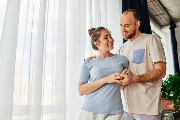 Positive couple in homewear holding hands while spending time together at home - Photo, image